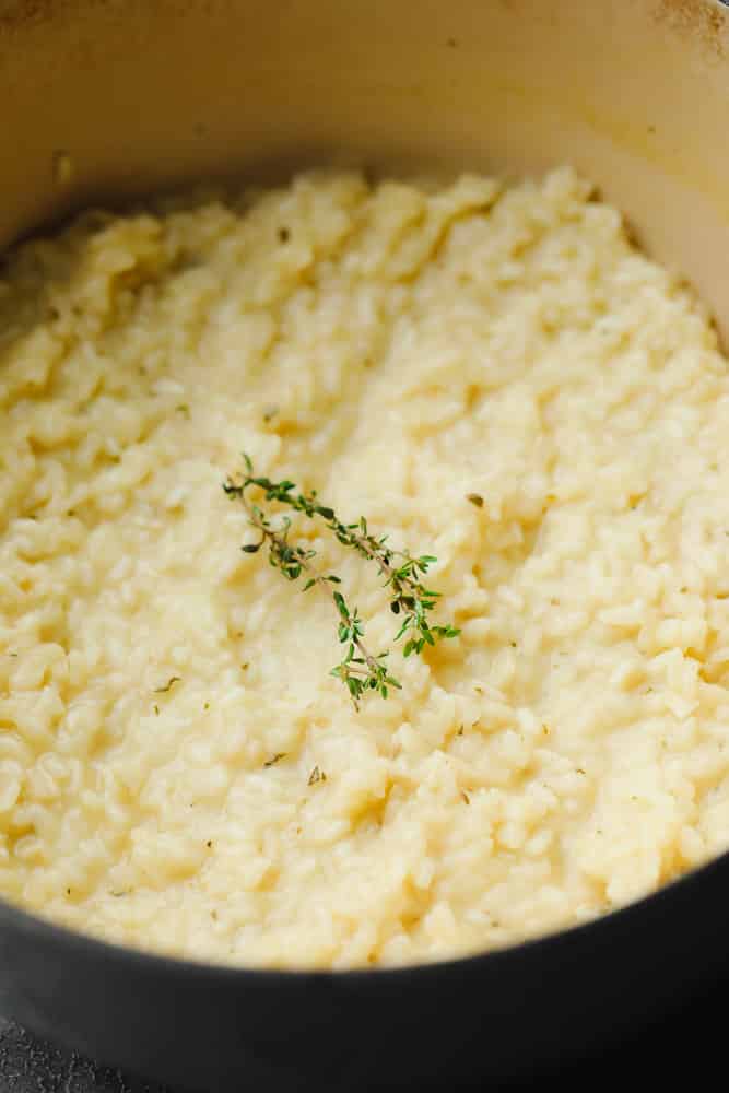 showing a pot of cooked rice mixture with thyme on top in a pot