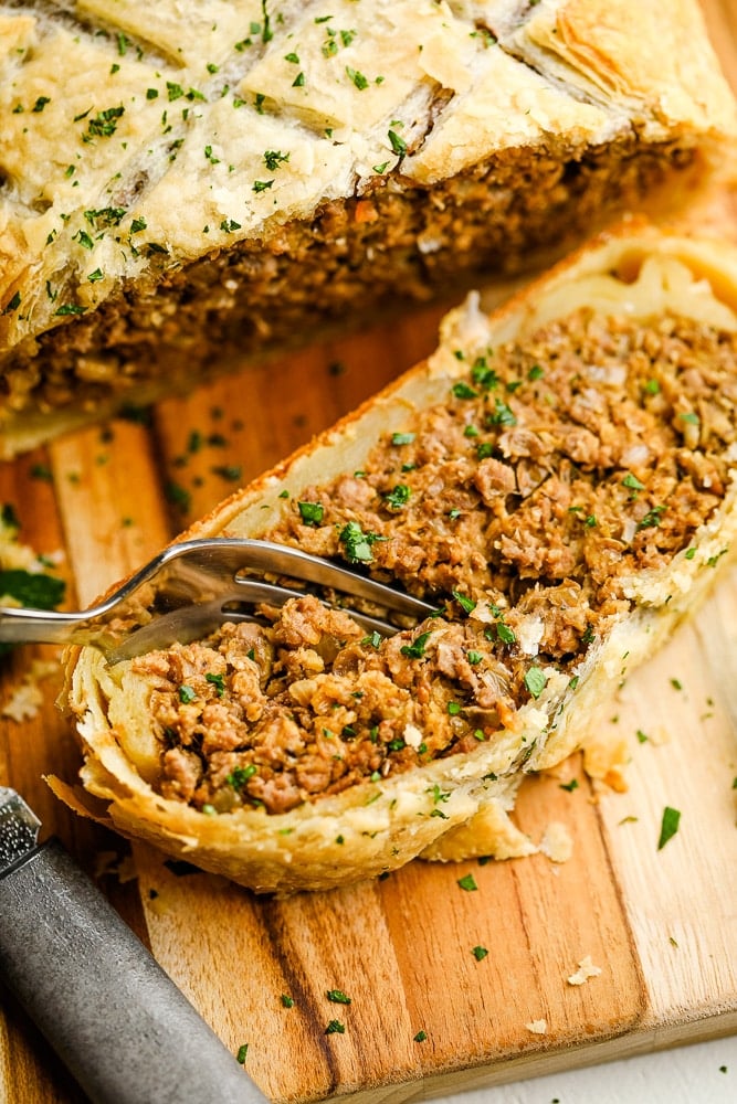 a fork scooping the meat filling out of a slice of vegan beef wellington.