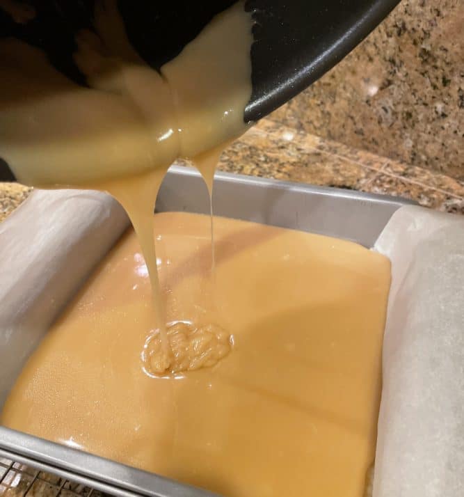caramel being poured into dish with parchment paper lining it