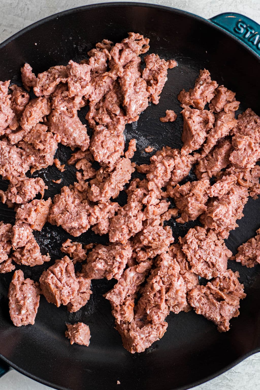 raw vegan ground beef cooking in a black skillet.