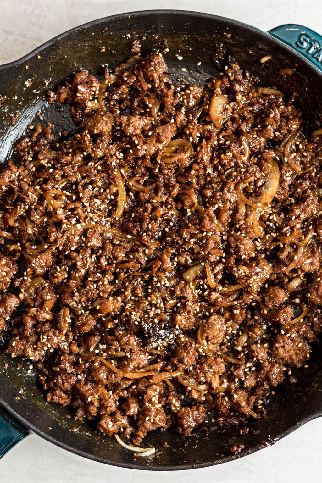 cooked vegan ground beef and onions covered in sesame seeds in a black skillet.