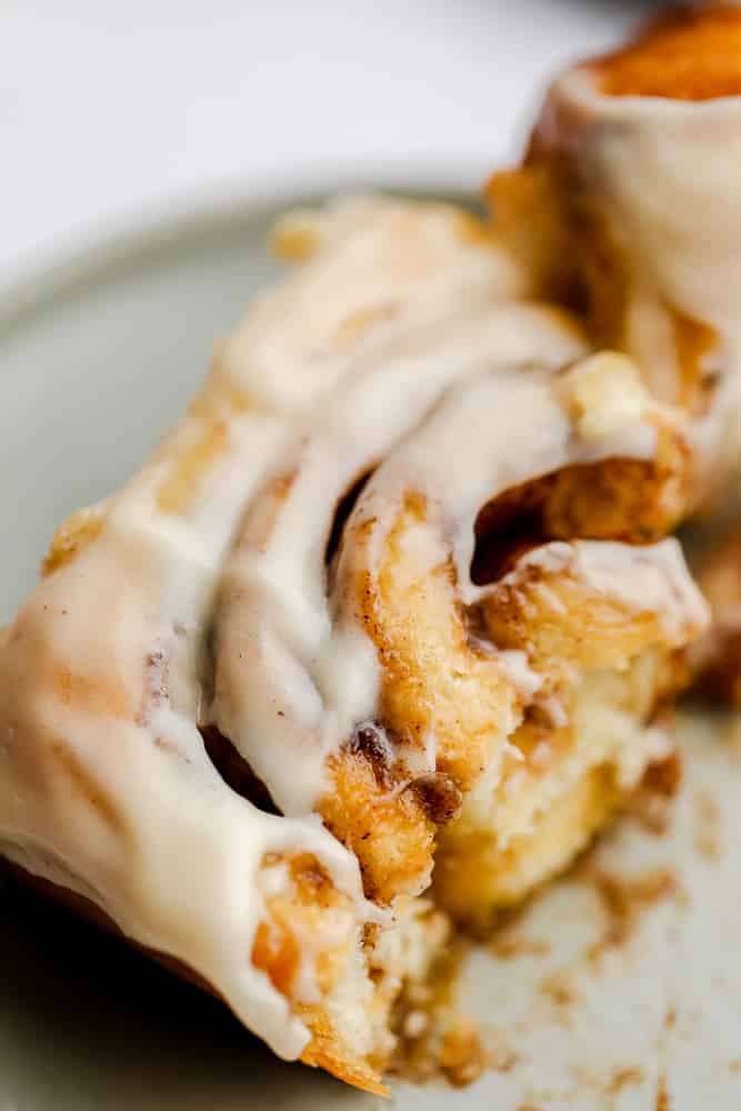 broken cinnamon roll showing gooey inside on a grey plate