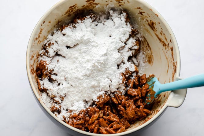 showing chocolate coated rice chex in a bowl and powdered sugar being added