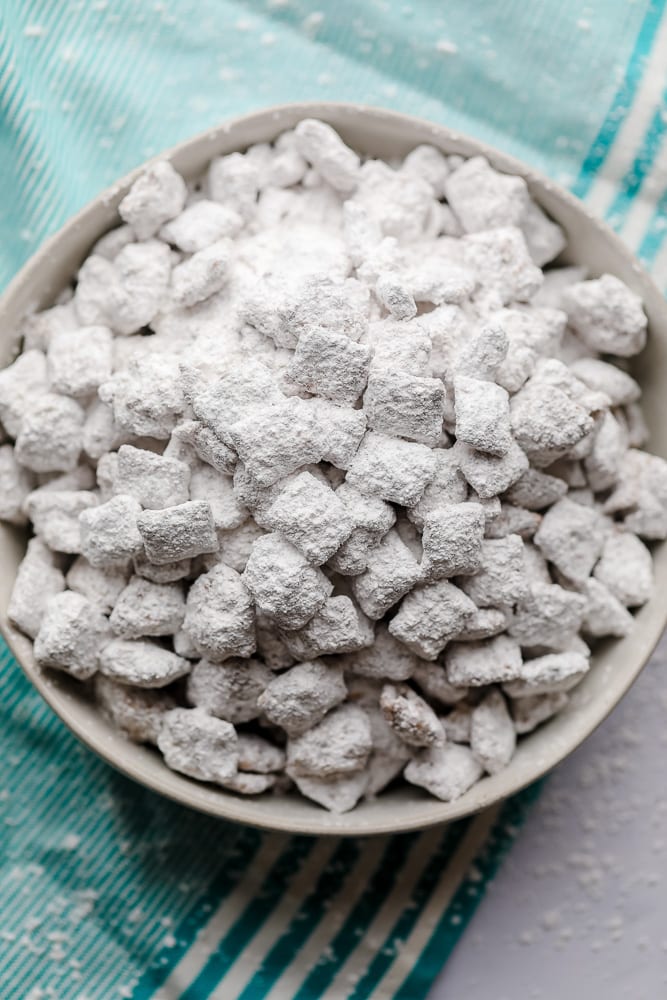 looking down on a bowl of vegan muddy buddies with blue striped towel