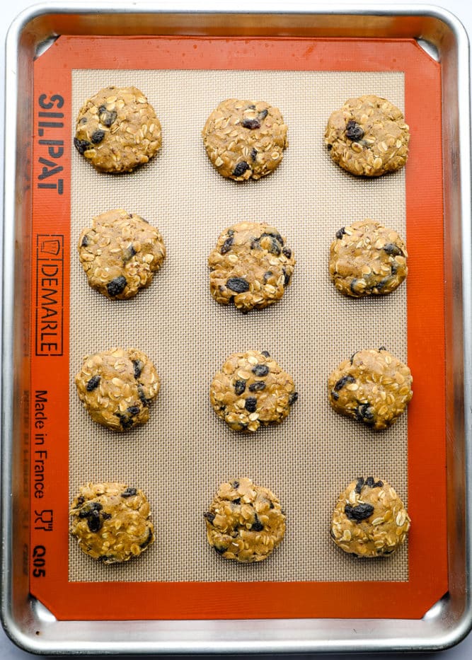 unbaked cookies on a silicone mat lined baking tray