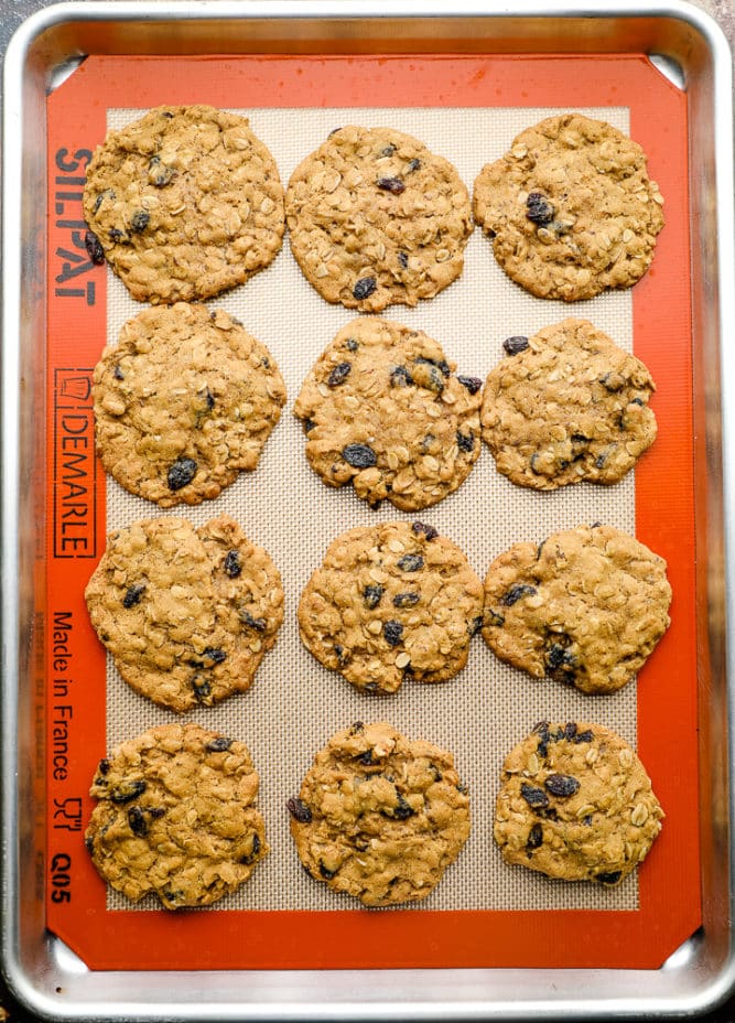 baking pan with cooked oatmeal raisin cookies on a silicone mat