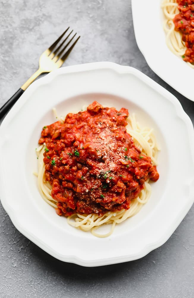 spaghetti noodles with homemade spaghetti sauce on top in a white bowl.