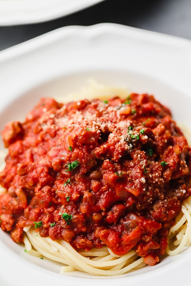 close up on spaghetti noodles with homemade spaghetti sauce on top in a white bowl.