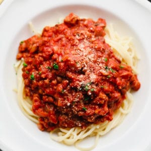 close up on spaghetti noodles with homemade spaghetti sauce on top in a white bowl.