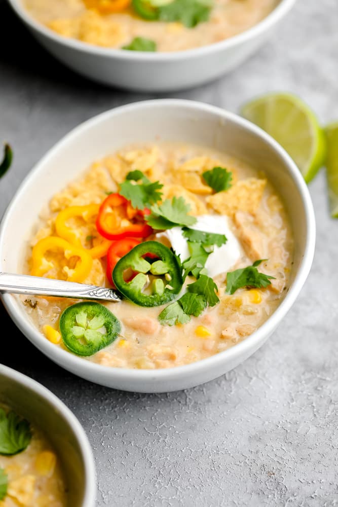 close up of vegan white chili with jalapenos and sour cream, cilantro on top