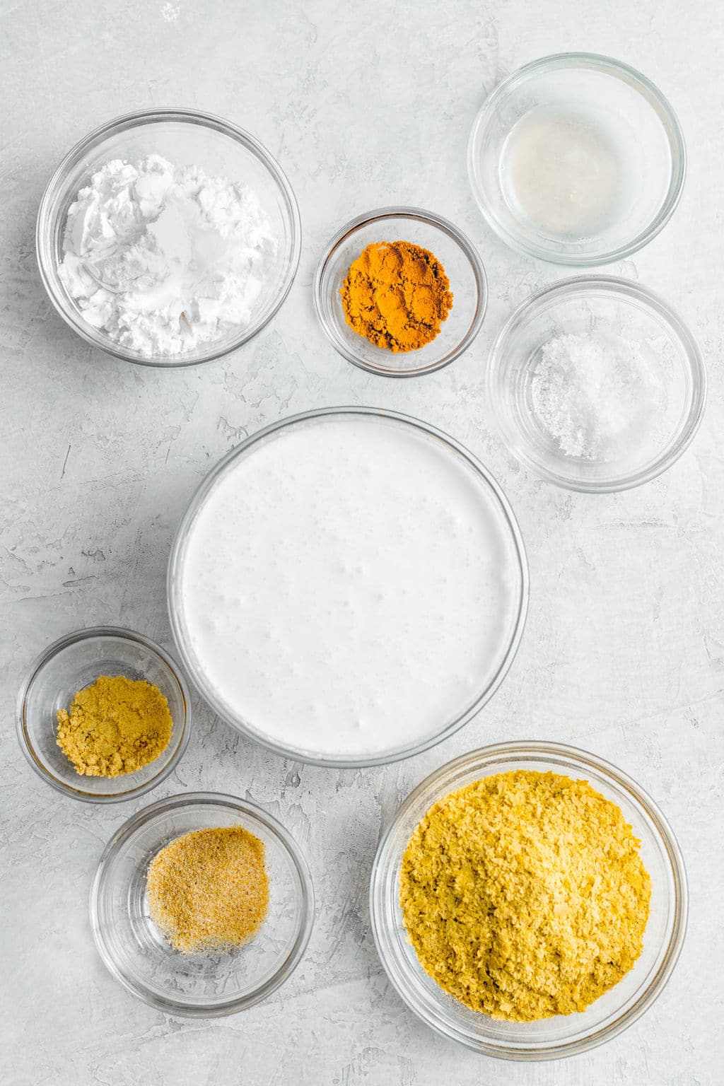 individual glass bowls filled with yellow seasonings, milk, and white powder.