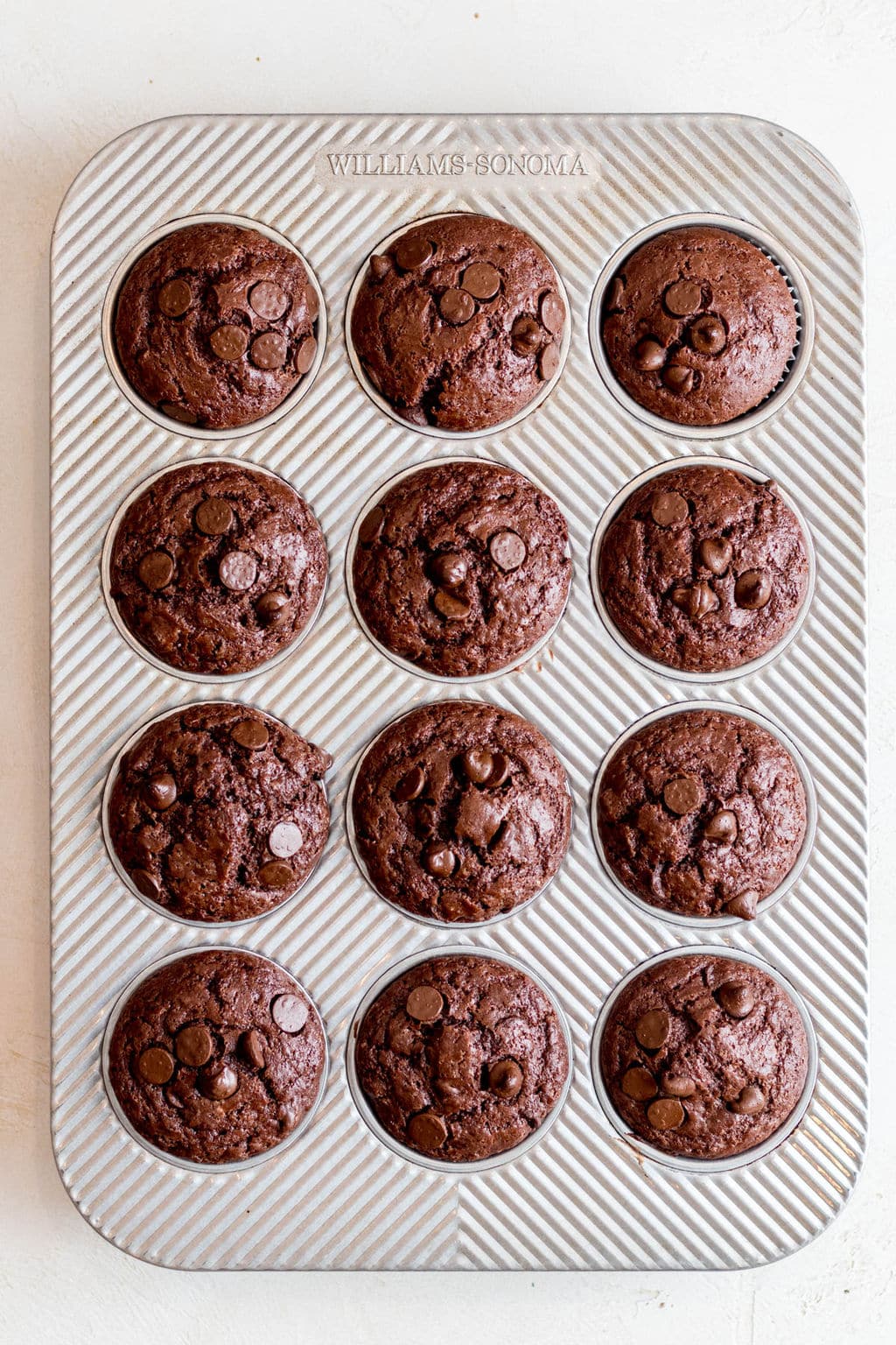baked chocolate muffins in a metal baking tin.