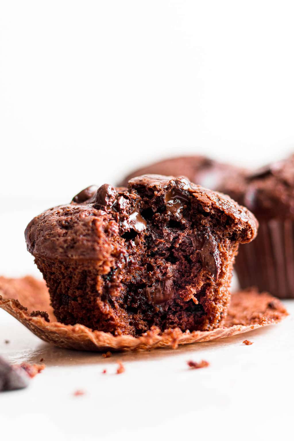 close up on a chocolate muffin with a bite out of it.