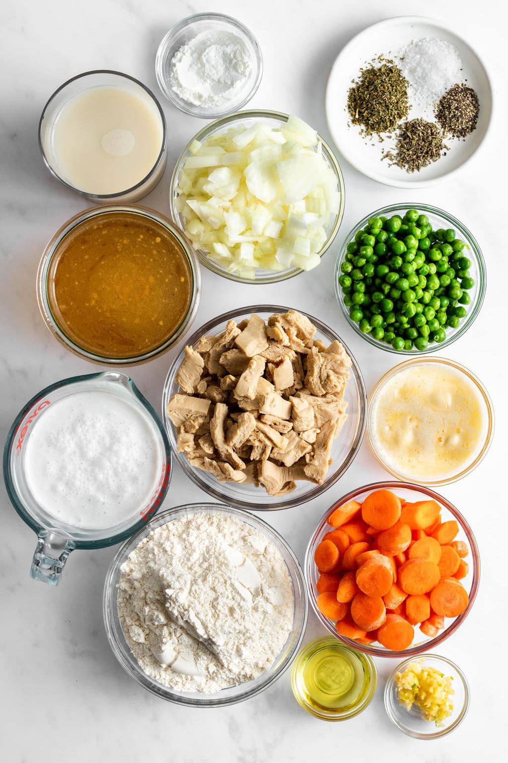 individual glass bowls filled with vegan chicken, vegetables, seasonings, flour, broth, and baking powder.