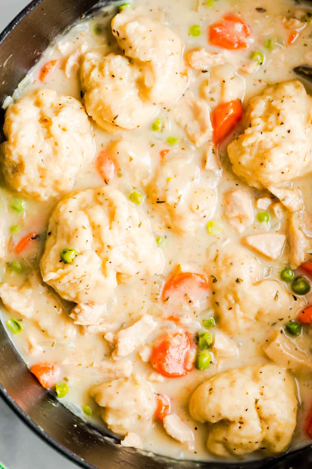 close up on vegan chicken soup and dumplings in a large black pot.