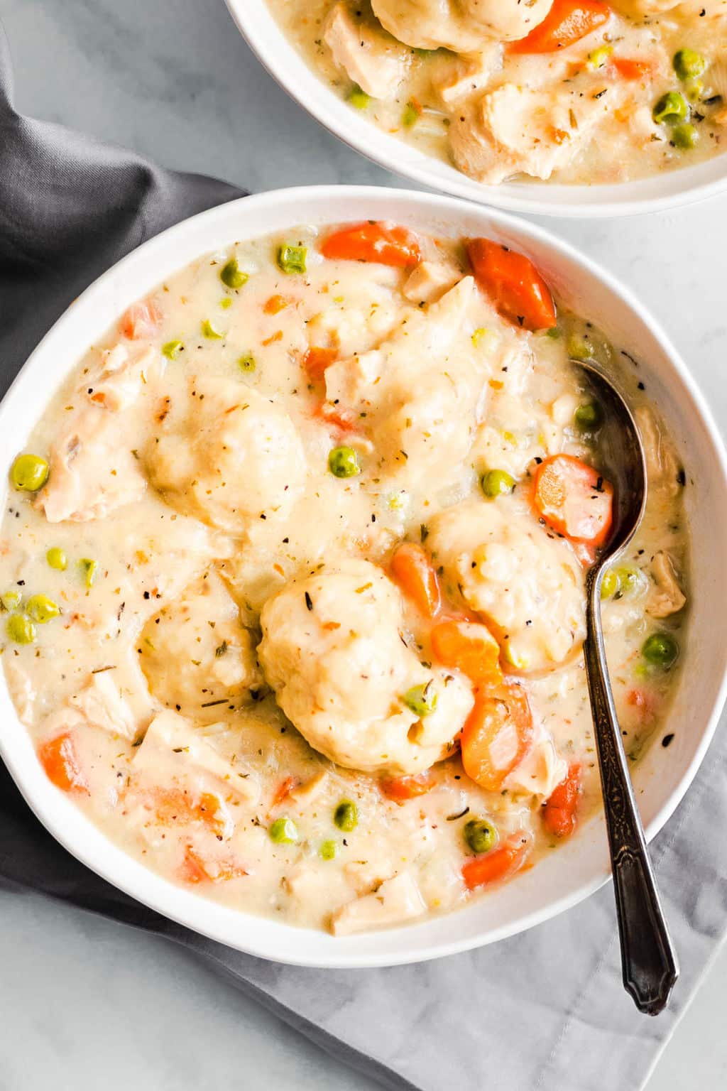 a white bowl filled with vegan chicken soup and dumplings.