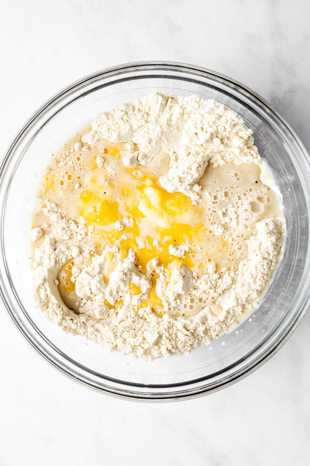 large glass bowl filled with flour, melted butter, and milk.