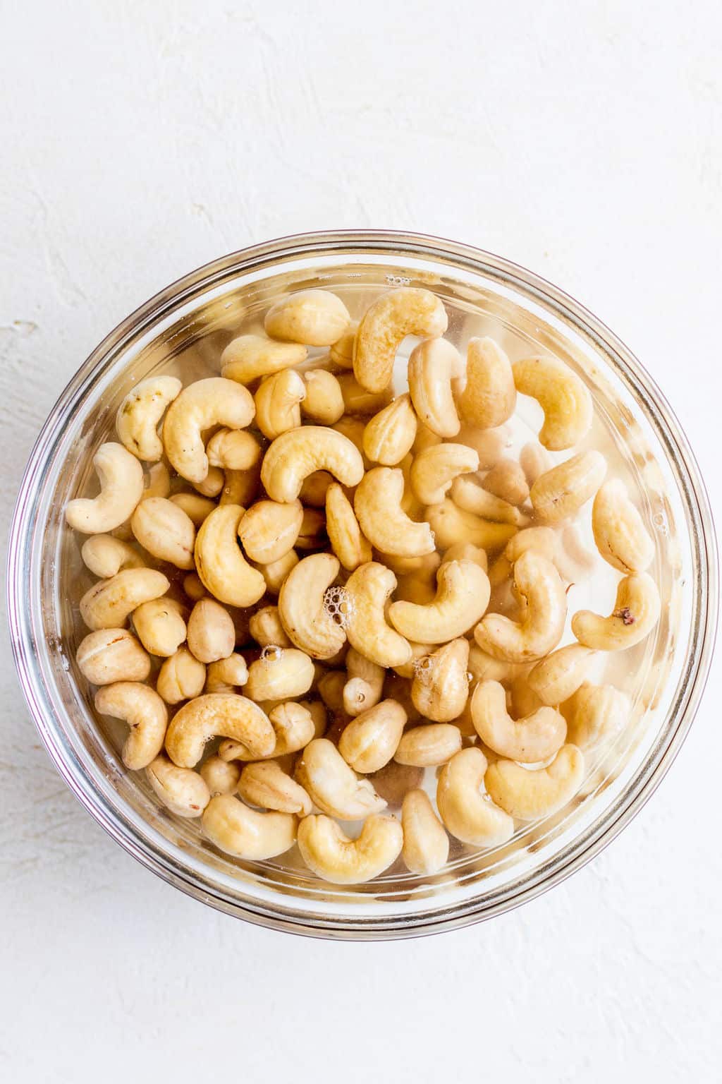 cashews submerged in water in a glass bowl.