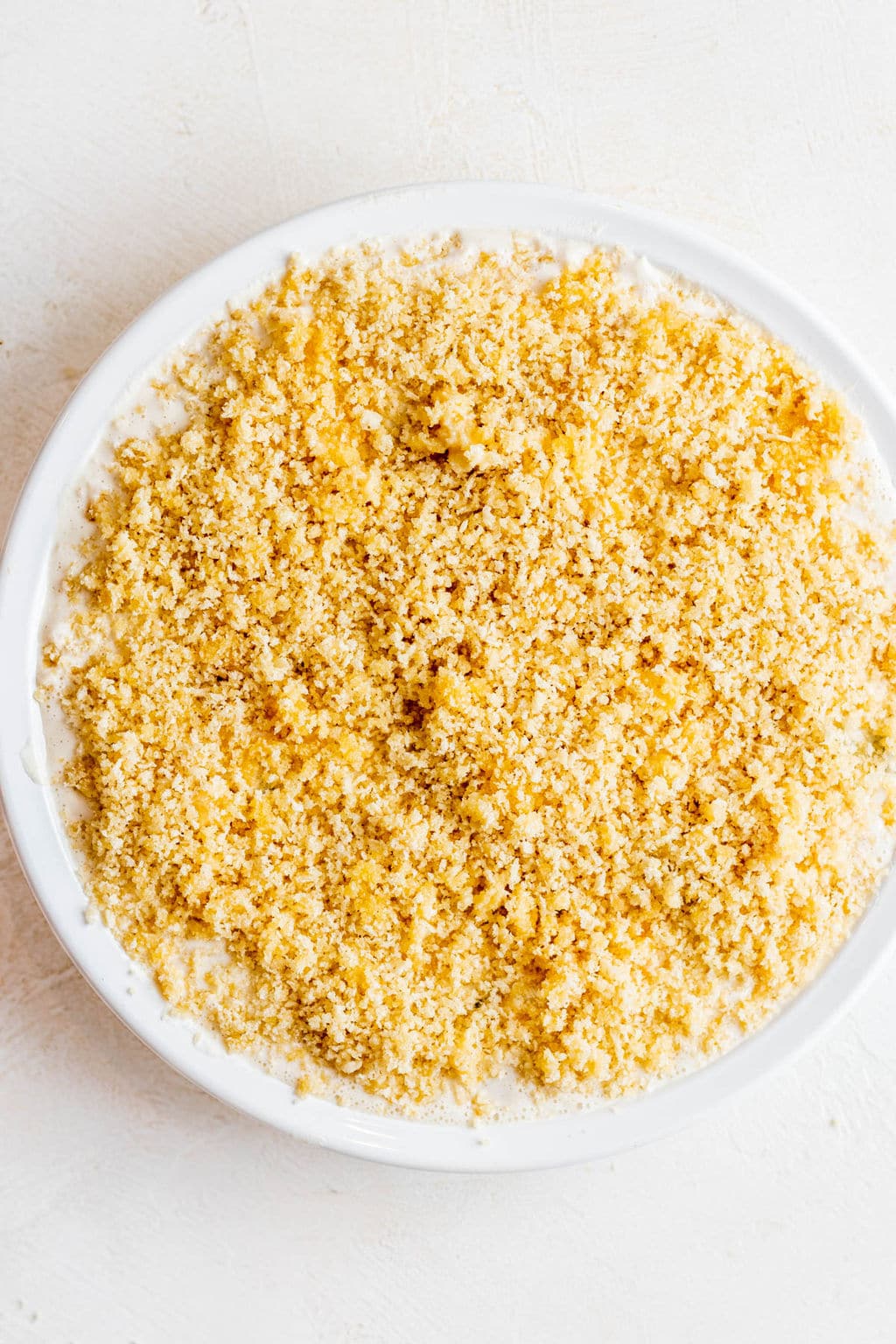 breadcrumbs on top of a white liquid in a white bowl.