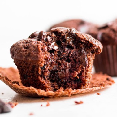 close up on a chocolate muffin with a bite out of it.