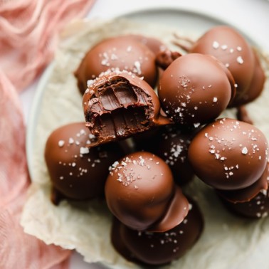 close up on a chocolate truffle with a bite taken out of it.