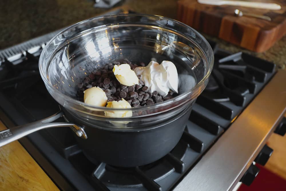 melting chocolate chips, butter, and coconut cream on the stove in a double broiler.