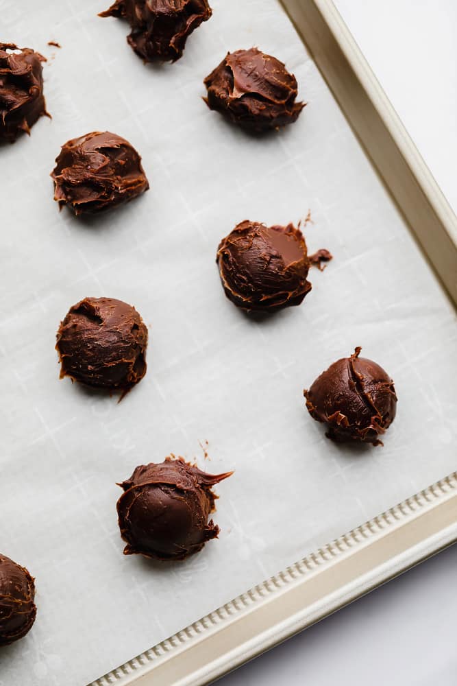 chocolate balls on a parchment-lined metal baking sheet.