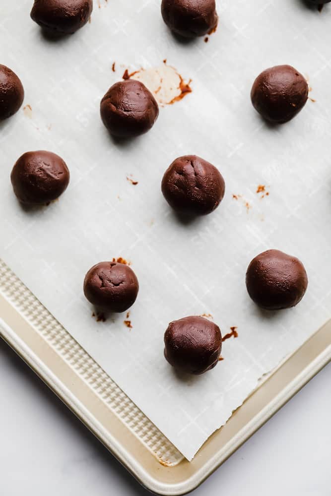 rolled chocolate balls on a parchment-lined metal baking sheet.