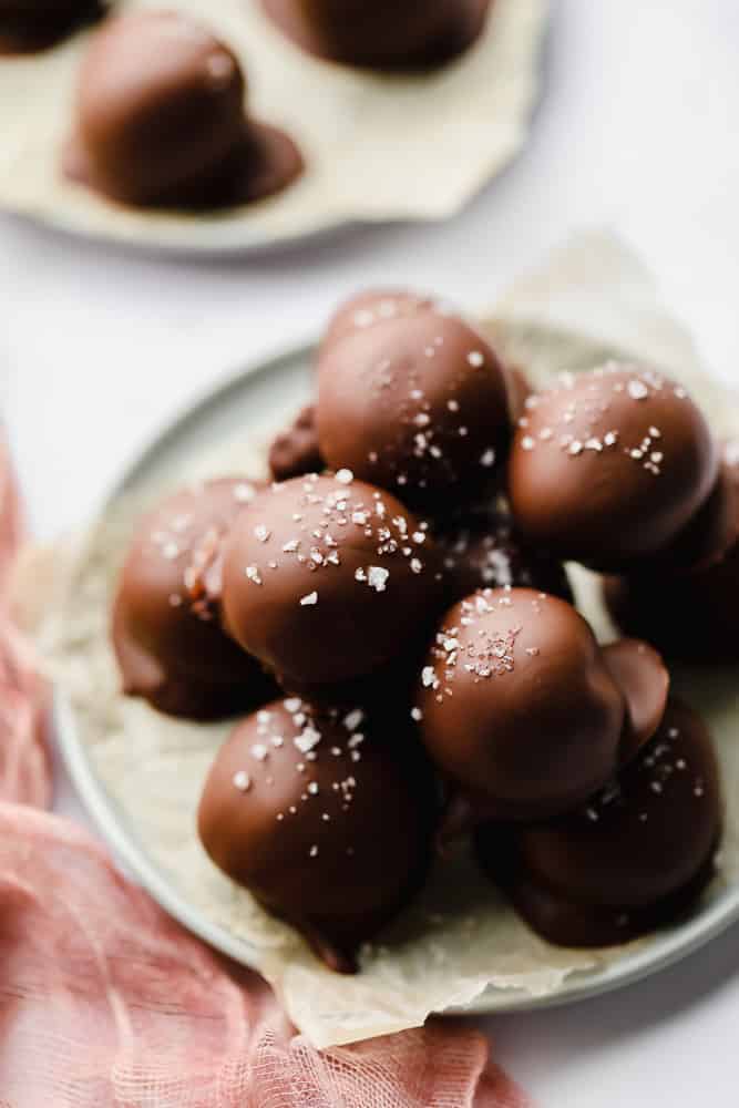 a pile of chocolate truffles on a piece of wax paper on a blue plate.