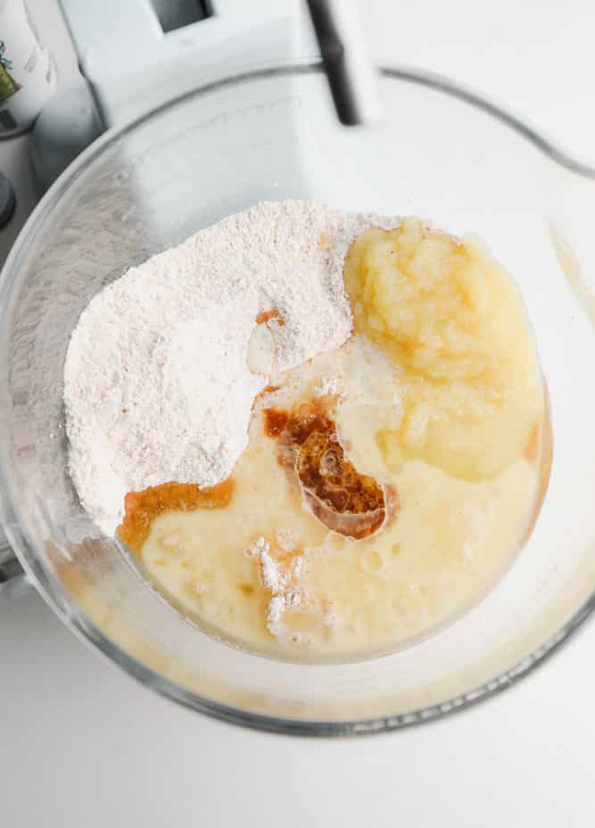 oil, applesauce and vanilla being added to dry ingredients in a bowl