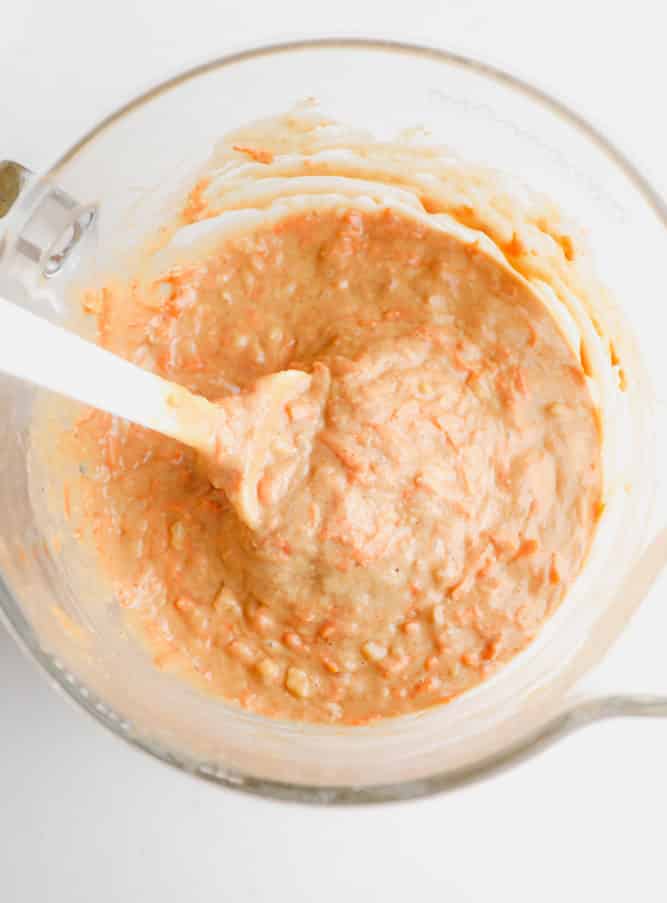 carrot cake batter in a clear bowl with a spatula