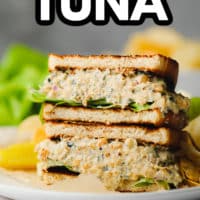 sandwich on a plate with a pickle and lettuce with text overlay reading vegan tuna