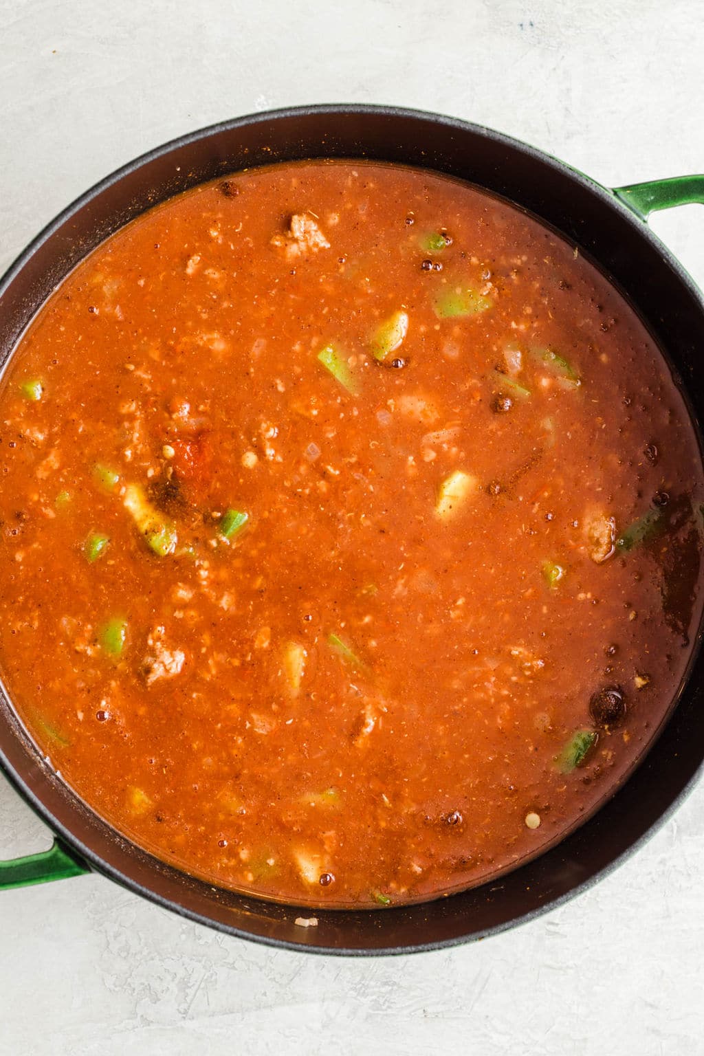 a large black pot filled with red tomato sauce and vegetables.