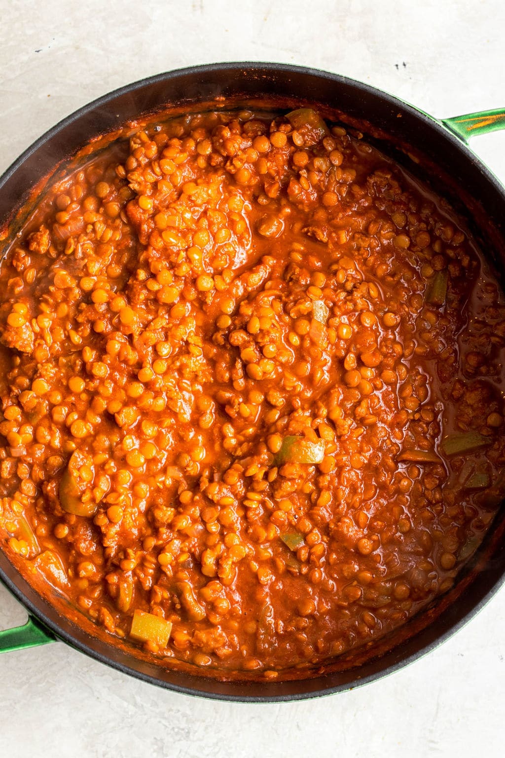 a large black pot filled with cooked lentils and tomato sauce.