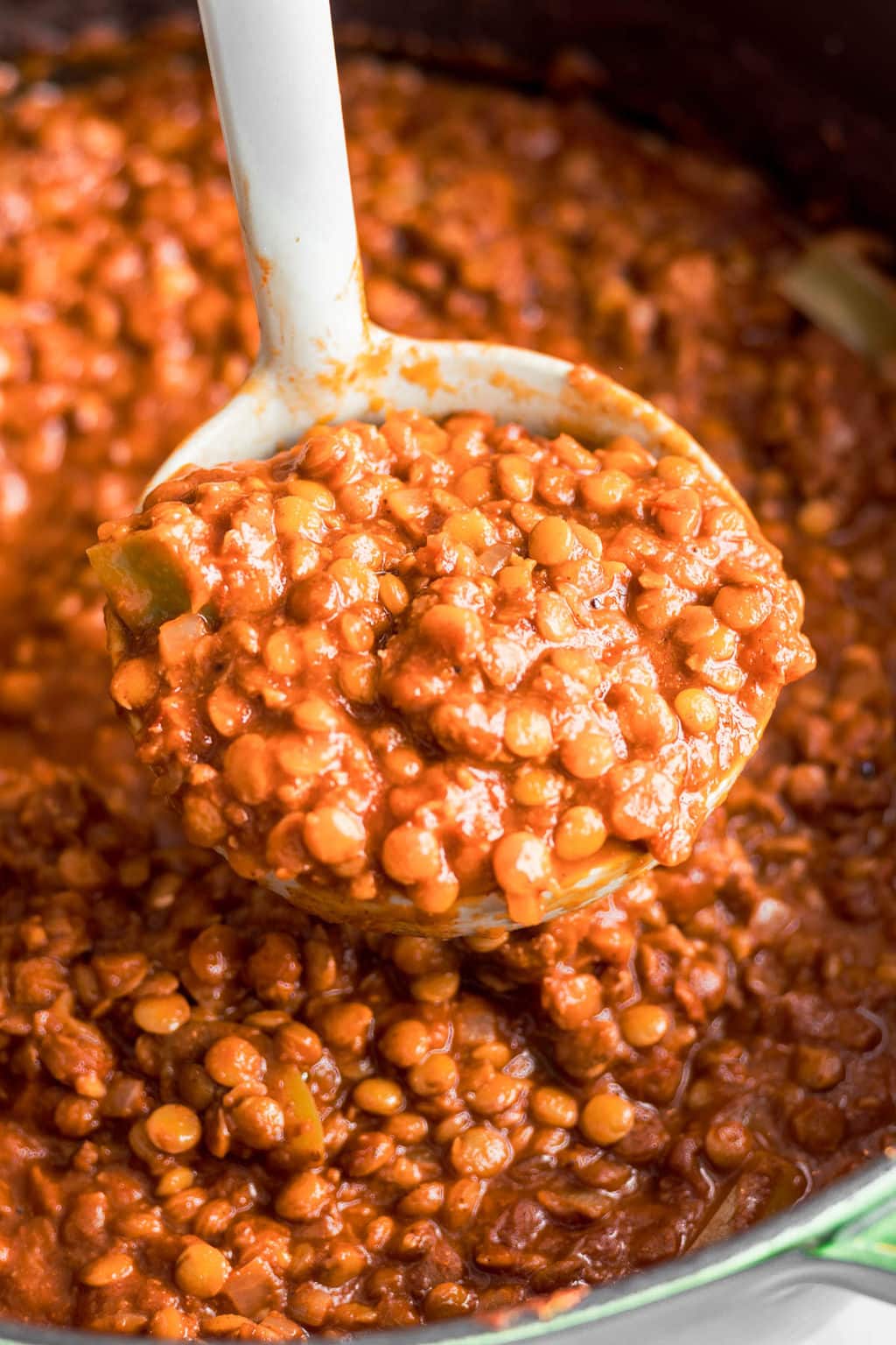 white ladle holding a scoop of lentil chili.