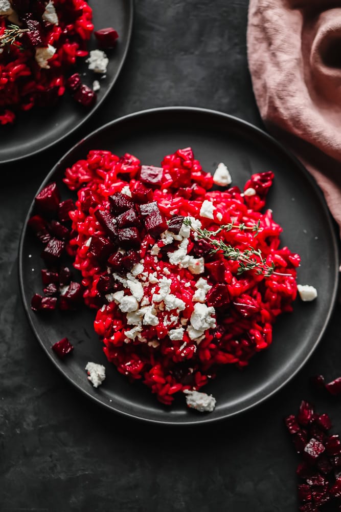 two plates of red risotto and cheese and beets