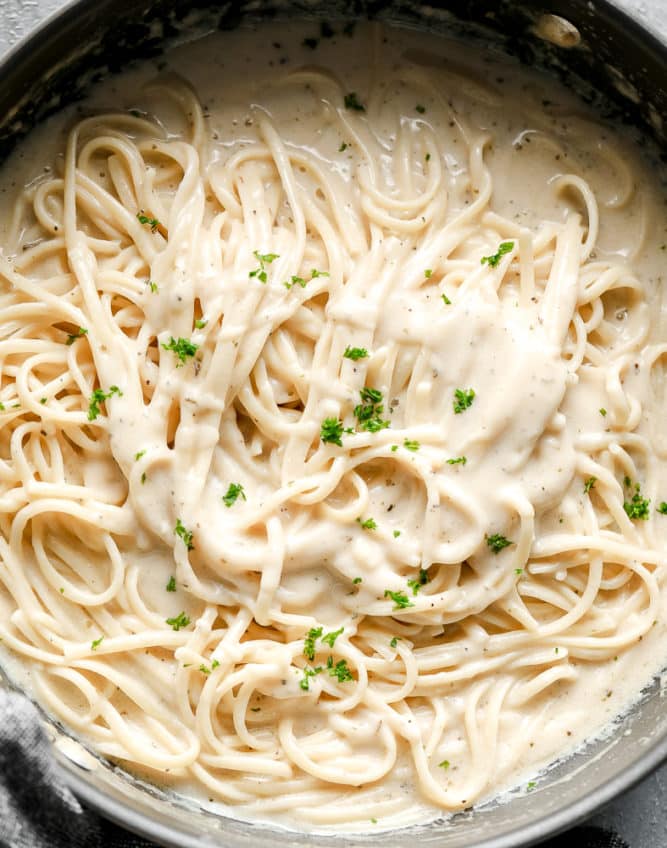 pan full of creamy pasta and white sauce, sprinkled with green parsley
