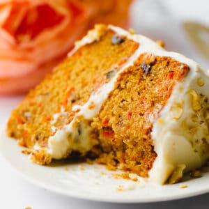 piece of orange cake on a plate with walnuts on the frosting