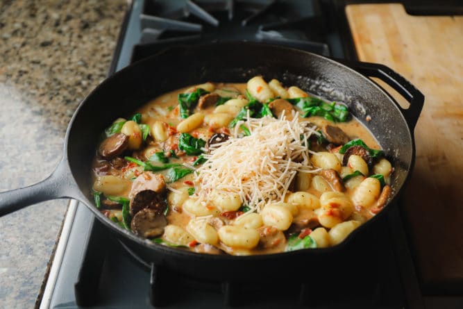 parmesan added to a pan with vegan gnocchi