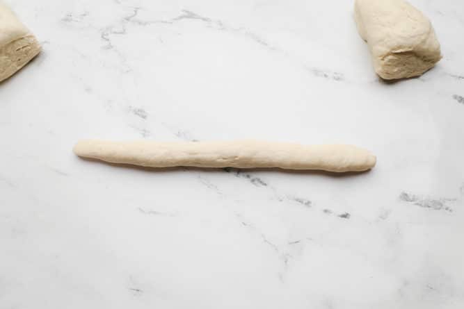 a log of dough on white marble background