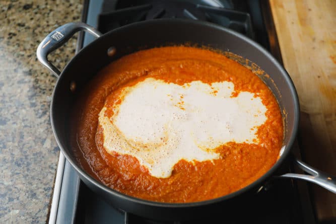 Sahne zur Tomatensauce in der Pfanne hinzufügen