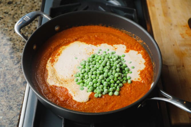 creamy and peas added to tomato sauce in pan