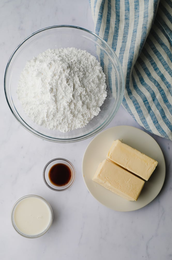 ingredients for frosting on white marble backdrop