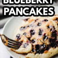 pinterest image of a fork taking a bite out of vegan blueberry pancakes.
