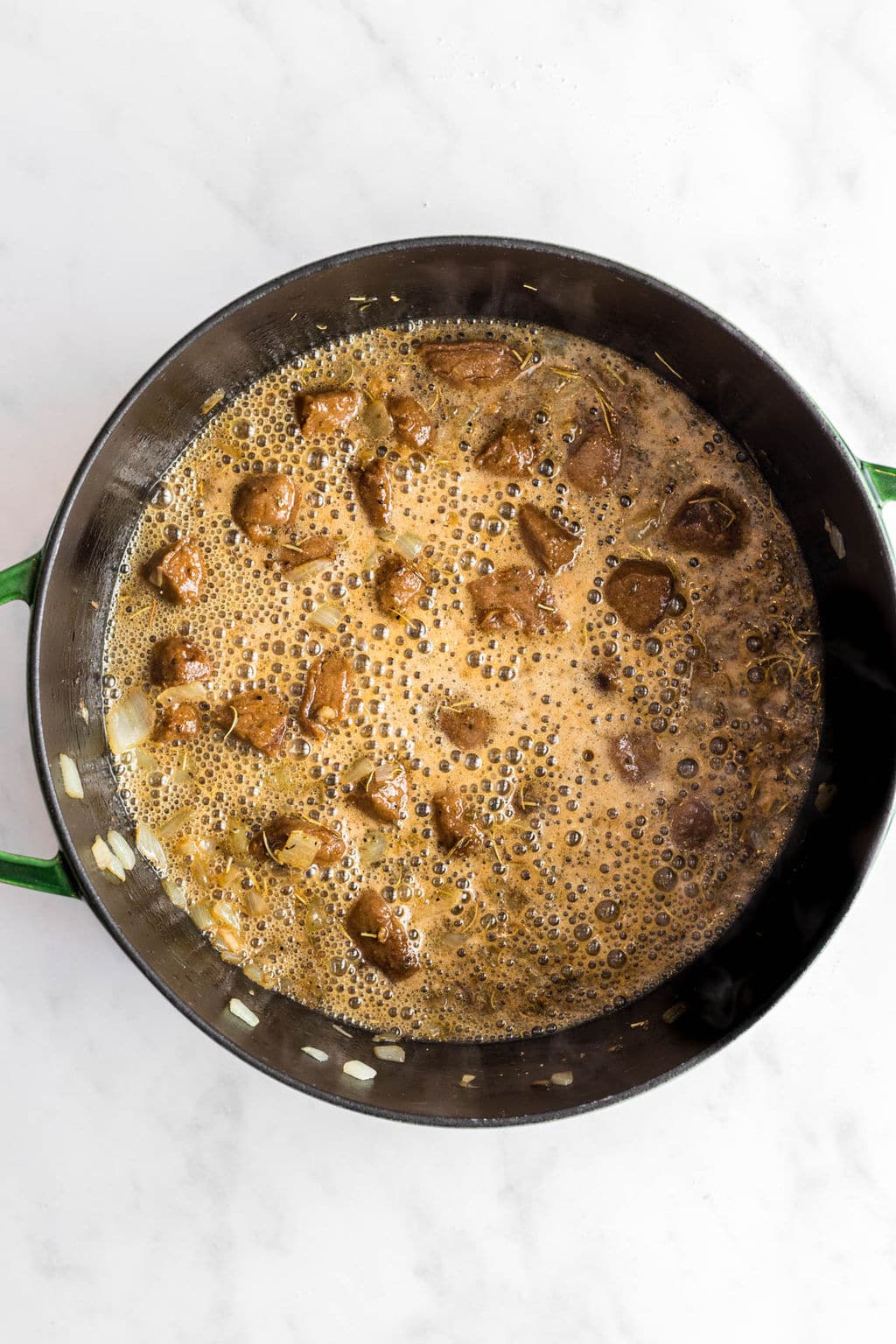 cooking a sauce and vegan sausage in a large black skillet.