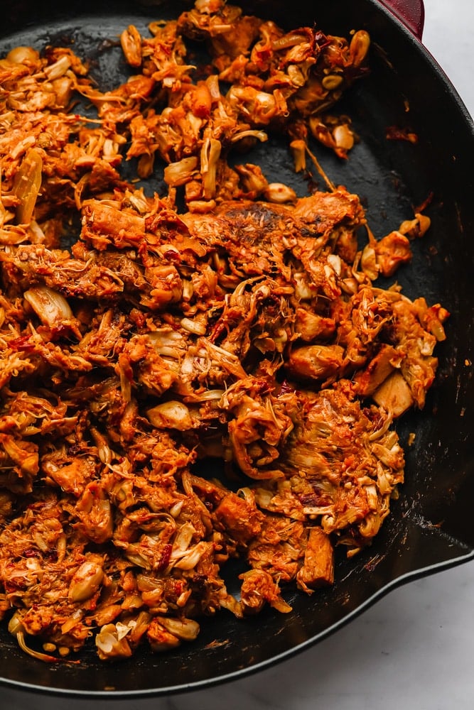 cooked, seasoned, and shredded jackfruit in a black skillet.