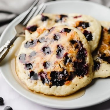 3 vegan blueberry pancakes on a white plate.