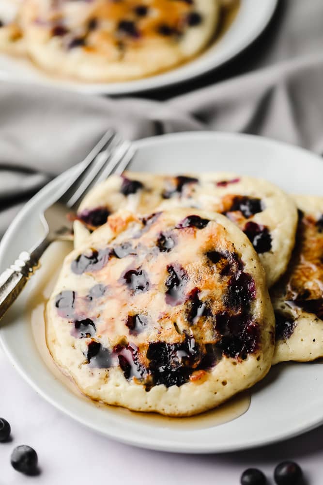 3 vegan blueberry pancakes on a white plate.