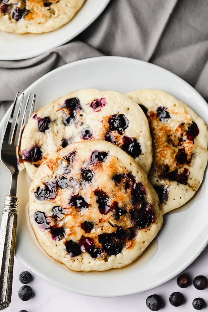 3 vegan blueberry pancakes on a white plate.