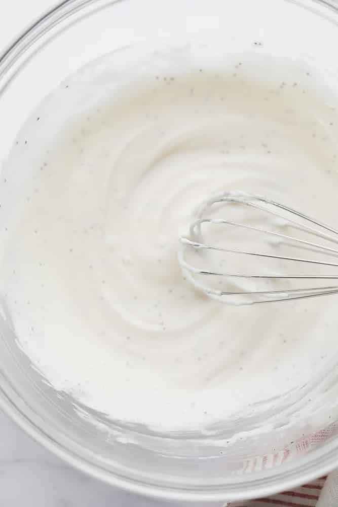 dressing for coleslaw in glass bowl with whisk